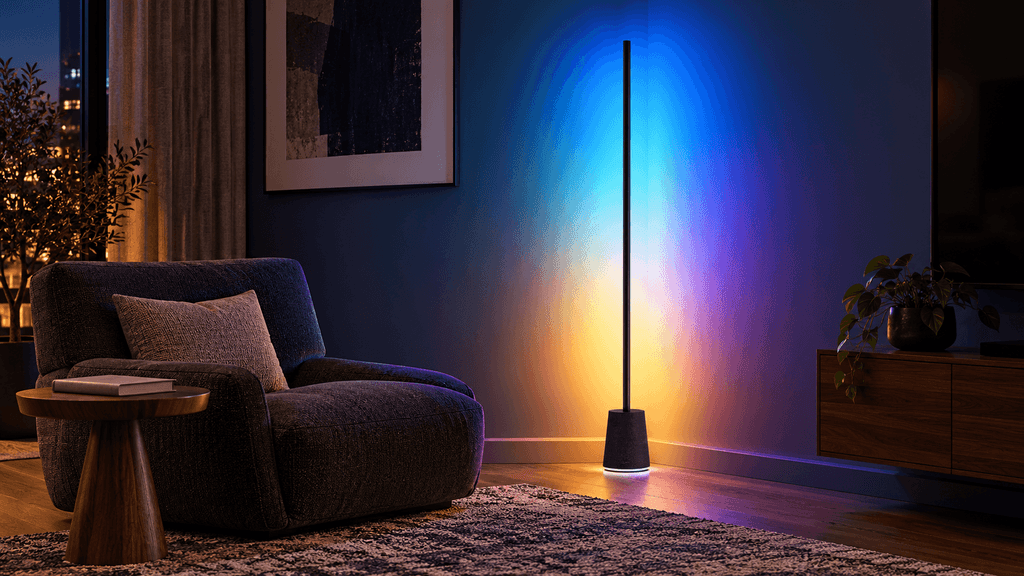 Govee Floor Lamp Pro casting multicolor ambient light across a dark modern living-room corner.